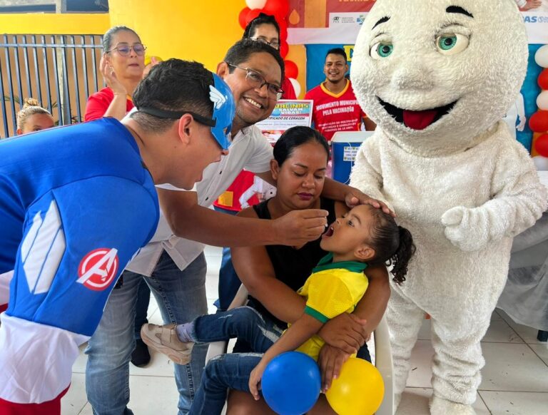Foto colorida mostra criança tomando vacina da gotinha