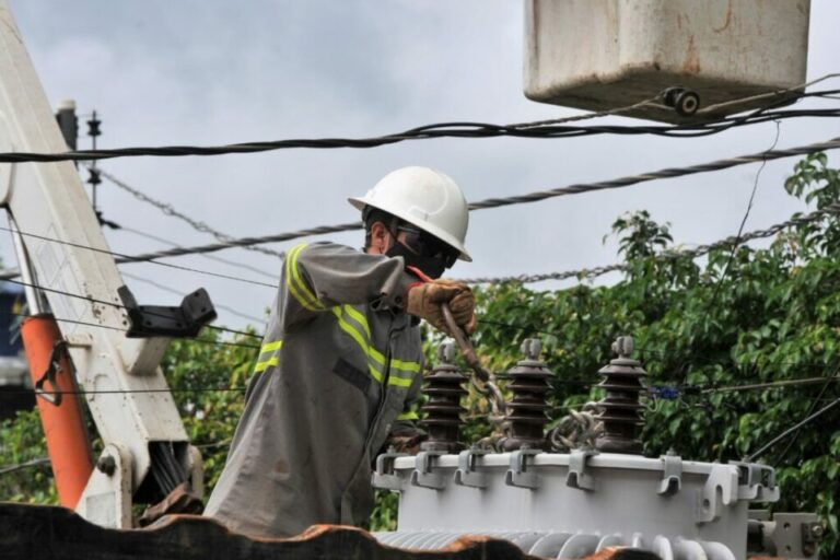 Imagem colorida mostra técnico fazendo manutenção em distribuidor de energia elétrica